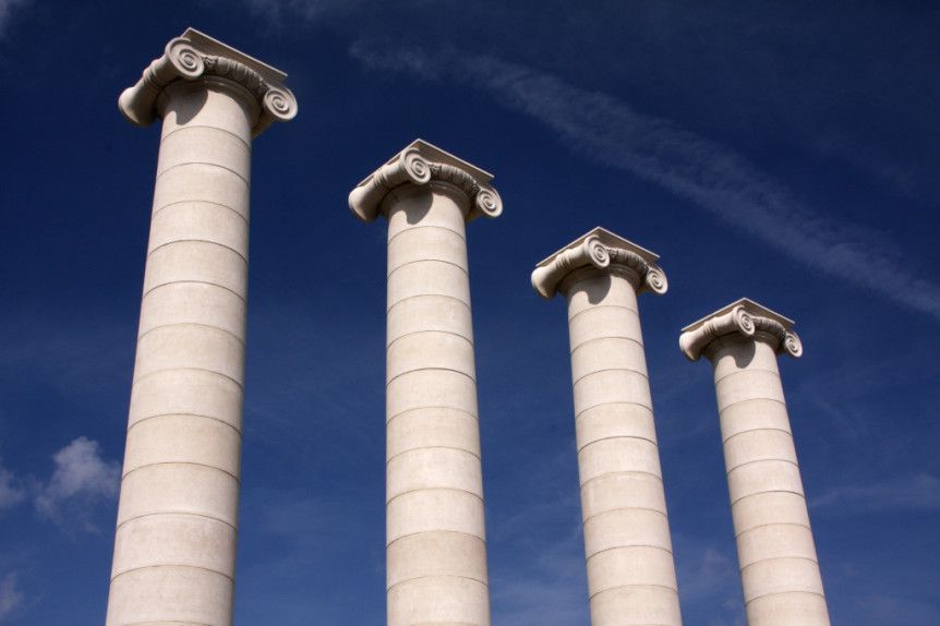 Four tall ionic stone columns against a deep blue sky